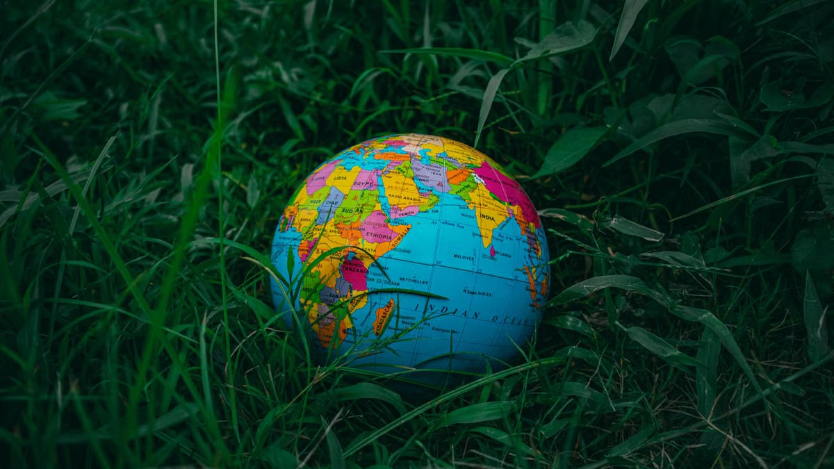 Vibrant world globe lying on lush green grass, symbolizing global exploration and nature.